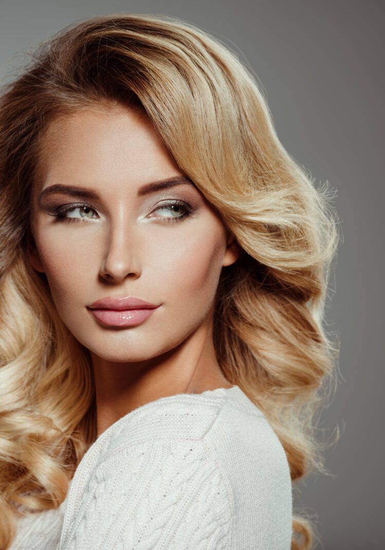 Photo of a beautiful young blond woman with curly hair. Closeup attractive sensual face of white woman. Smokey eye makeup.